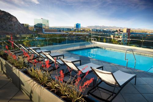 a pool on the roof of a building with chairs and flowers at Hyatt House Tempe Phoenix University in Tempe