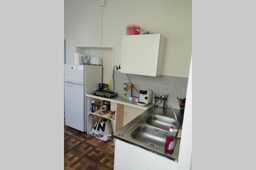 eine Küche mit einer Spüle und einem Kühlschrank in der Unterkunft Au calme, devant le port, studio indépendant in Lere