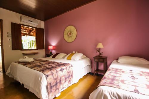two beds in a room with pink walls at Pousada Arvoredo in Pirenópolis