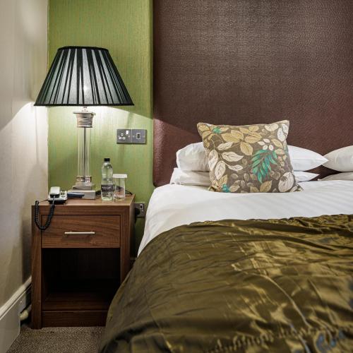 a hotel room with a bed and a lamp on a night stand at The Royal Oak Hotel, Welshpool - The Coaching Inn Group in Welshpool