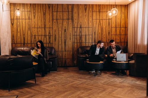 three people sitting in chairs in a room with laptops at Kulikovskiy hotel in Kharkiv