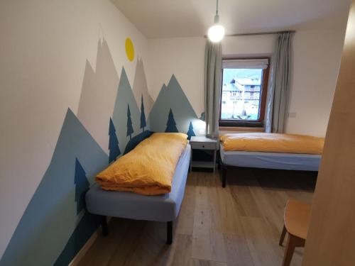 1 dormitorio con 2 camas y una pared con montañas en Appartamento Engy, en Livigno