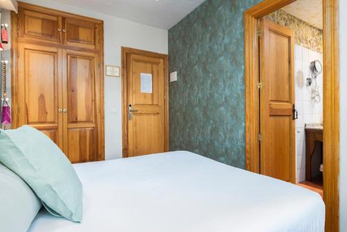 a bedroom with a white bed and wooden doors at El Torreon de Navacerrada in Navacerrada