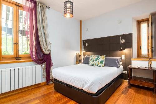 a bedroom with a bed and a desk and windows at El Torreon de Navacerrada in Navacerrada
