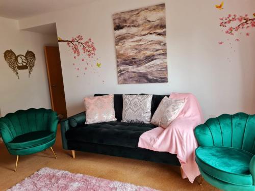 a living room with a black couch and two chairs at Emerald Blossom-Central Warrington, Luxurious Yet Homely, WiFi, Secure Parking in Warrington