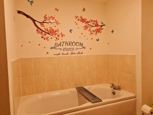 a bathroom with a bath tub and a sign on the wall at Emerald Blossom-Central Warrington, Luxurious Yet Homely, WiFi, Secure Parking in Warrington