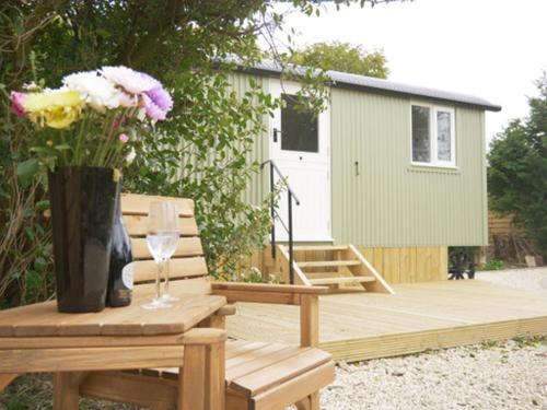 a wooden bench with a vase of flowers and a vase of wine glasses at Wolstonbury Getaway in Hassocks