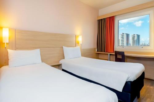 um quarto de hotel com duas camas e uma janela em ibis Sao Paulo Interlagos em São Paulo