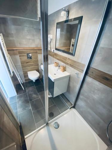 a bathroom with a shower with a sink and a toilet at Apartamenty Różany Ogród in Łeba