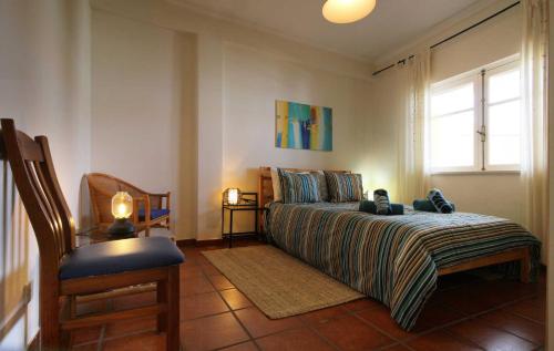 Un dormitorio con una cama y una silla y una ventana. en Apartamento Azur, en Vila Nova de Milfontes