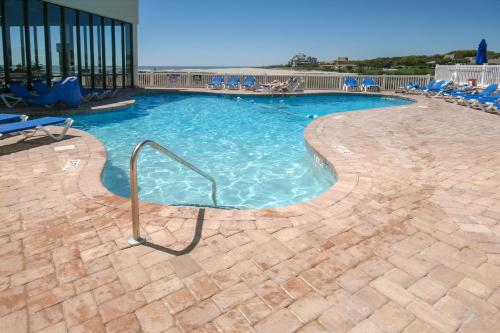 a large swimming pool with blue chairs in a building at Sands Beach Club in Myrtle Beach