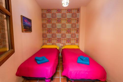 two beds in a room with pink and yellow cushions at tuGuest Aljibe del Rey Apartment in Granada