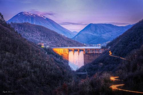 a dam in a valley with a mountain in the background at Stanza con terrazzo Vista Lago - LAKEHOLIDAY in Castel di Tora