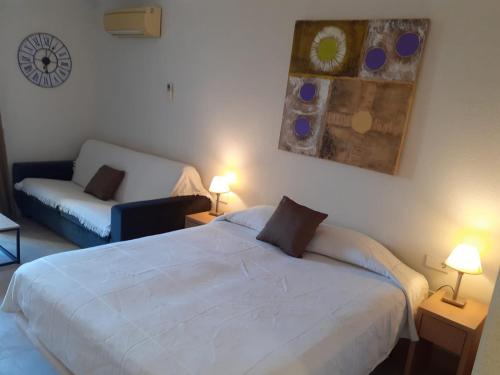 ein Schlafzimmer mit einem weißen Bett und einem Sofa in der Unterkunft Benal Beach Estudio Playa in Benalmádena