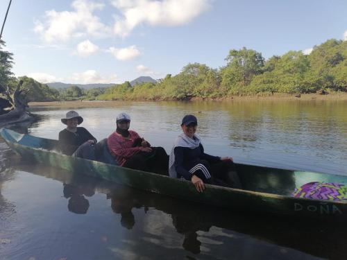 three people sitting in a canoe on the water at Casa Colibrí in Nuquí
