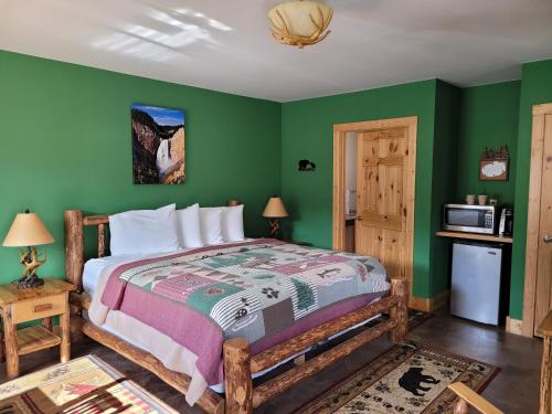 a bedroom with a bed and a green wall at Yellowstone Basin Inn in Gardiner