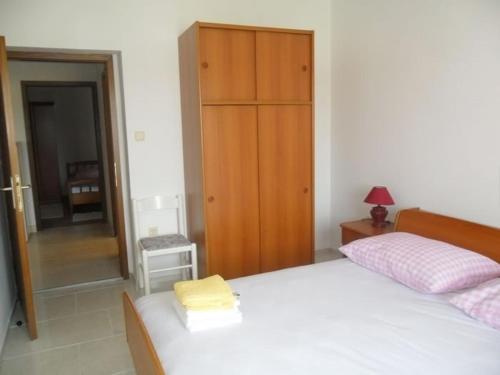 a bedroom with a bed and a wooden cabinet at Apartment in Palit with sea view, balcony, Wi-Fi (4606-2) in Mundanije