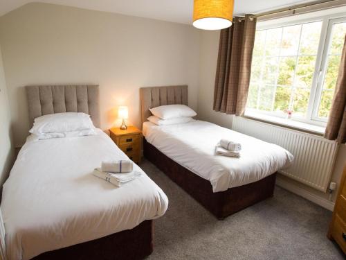 two beds in a small room with two windows at Catref in Llangollen