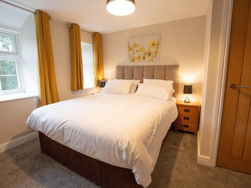 a bedroom with a large white bed with yellow curtains at Minafon in Llangollen