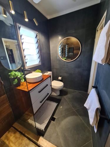 a bathroom with a sink and a toilet and a mirror at 3 Bedroom City Fringe Townhouse with Spa & Courtyard in Darwin