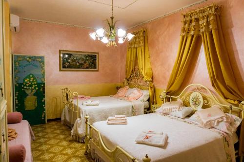 een slaapkamer met 2 bedden, gele gordijnen en een kroonluchter bij Bellavista Versilia in Pietrasanta