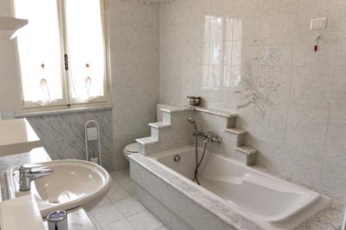 a white bathroom with a tub and a sink at Bellavista Versilia in Pietrasanta