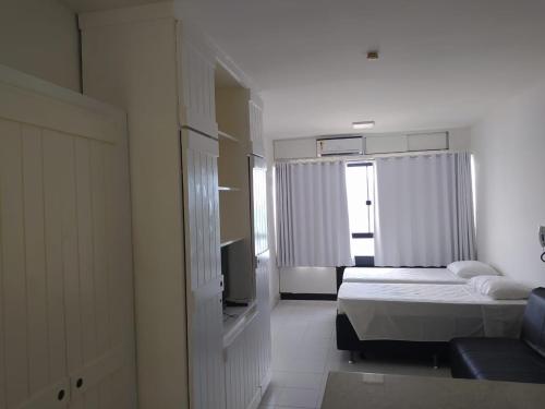 ein Schlafzimmer mit einem Bett und einem TV in der Unterkunft Flat no Farol da Barra in Salvador