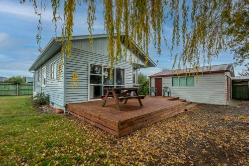 a picnic table on a wooden deck in front of a house at 5 Amuri Avenue in Hanmer Springs