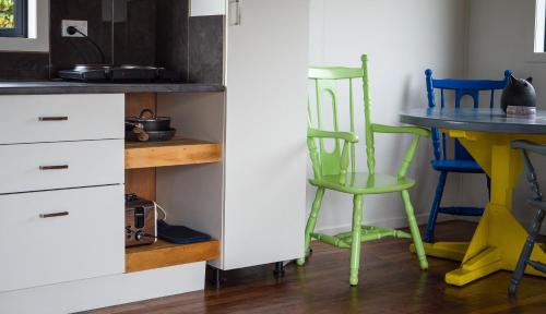 a kitchen with green chairs and a table at Honey Cottage in Ettrick in Millers Flat