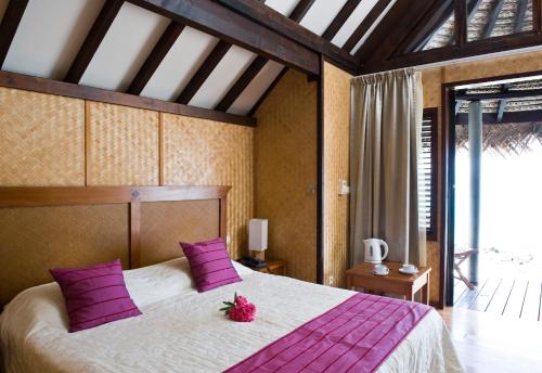 a bedroom with a large bed with purple pillows at Maitai Rangiroa in Avatoru