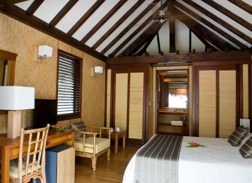 a bedroom with a bed and a desk and a chair at Maitai Rangiroa in Avatoru