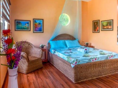 a bedroom with a bed and two wicker chairs at Blue Moon Guesthouse in Puerto Princesa City