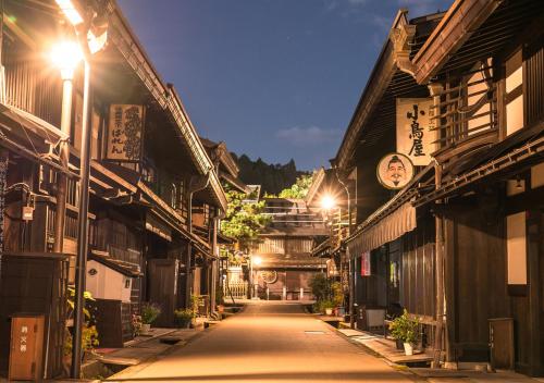 an empty street at night with buildings and lights at 筋肉と自然と遊ぶ宿 田島館 in Takayama