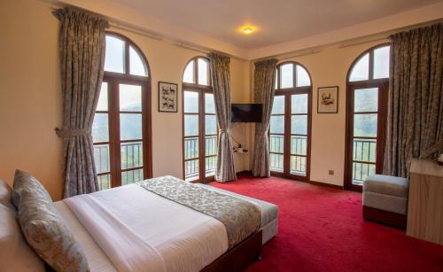 a bedroom with large windows and a large bed at The Wind Castle in Nuwara Eliya