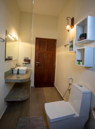 a bathroom with a toilet and a sink and a wooden door at The Wind Castle in Nuwara Eliya