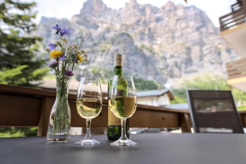 a bottle of wine and two glasses on a table at Hotel Beau-Séjour in Leukerbad