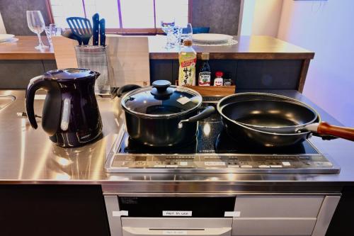 two pots and pans on a stove in a kitchen at Manabi-stay Takayama SAKURA in Takayama