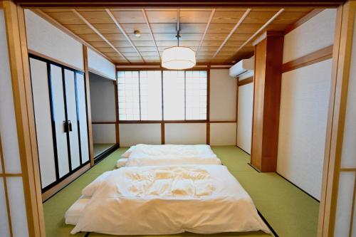 Habitación con 3 camas y ventanas. en Manabi-stay Takayama SAKURA 提携駐車場利用可 古い町並みまで徒歩1分 最大9名宿泊可能な一等地で人工温泉を楽しむ, en Takayama