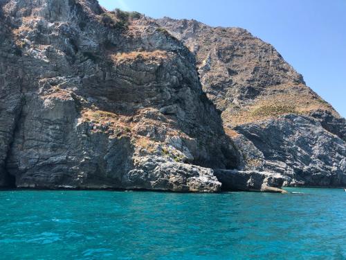 a rocky cliff next to the ocean with blue water at Al Saliceto Hotel in Patti