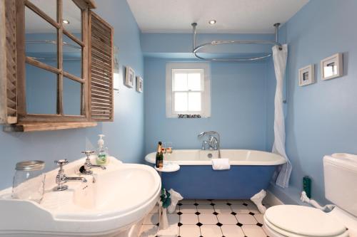 a blue bathroom with a tub and a toilet and a sink at The Nest Canterbury -Central-Ultra WIFI in Canterbury