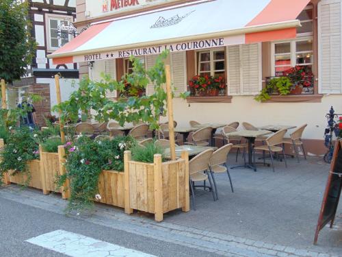 a restaurant with tables and chairs and plants on the sidewalk at La Couronne à Wissembourg in Wissembourg