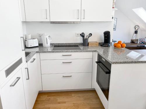 a white kitchen with white cabinets and oranges on the counter at Modern & Stylisch - Penthouse-Feeling nahe Flughafen München in Freising