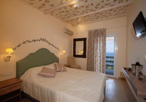 a bedroom with a bed and a tv and a window at Venus Beach Hotel in Nea Stira