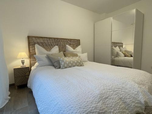 a bedroom with a large white bed with a large mirror at Ferienwohnung am Park in Badenweiler