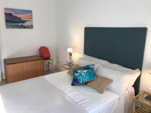 a bedroom with a white bed with a blue pillow on it at Océano Home in Ayamonte