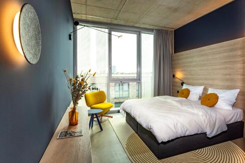 a bedroom with a large bed and a yellow chair at KONCEPT HOTEL Josefine in Cologne