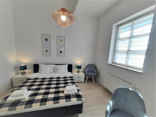 sypialnia z łóżkiem, krzesłem i oknem w obiekcie Apartamenty Jantar w mieście Giżycko