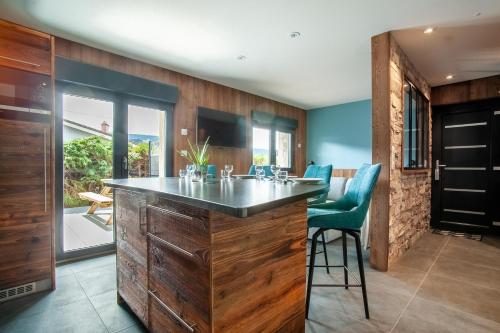 une cuisine avec une grande île dotée de chaises bleues dans l'établissement Le Refuge, à Gérardmer