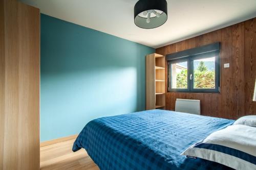 une chambre avec un lit bleu et une fenêtre dans l'établissement Le Refuge, à Gérardmer