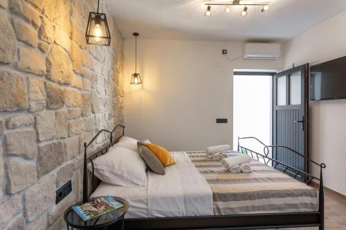 a bedroom with a bed against a stone wall at TEONA Luxury Studio Apartment with jacuzzi and garden view in Sali